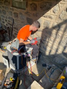 Learning how to install an AC disconnect on a stone wall.