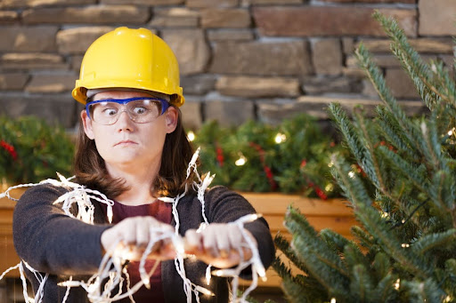 Homeowner wearing hardhart while holding holiday lights.