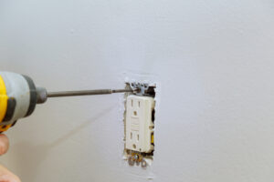 Electrician drilling new outlet into the wall.