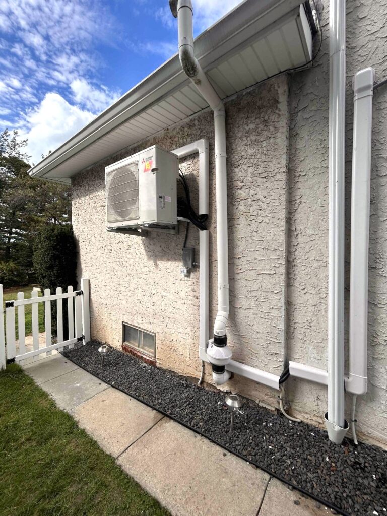 Outdoor Mitsubishi ductless mini-split condenser installed by GEN3 Electric & HVAC in Roxborough, Philadelphia, mounted on wall brackets with white PVC linehide and insulated refrigerant lines for a clean, weather-protected finish.