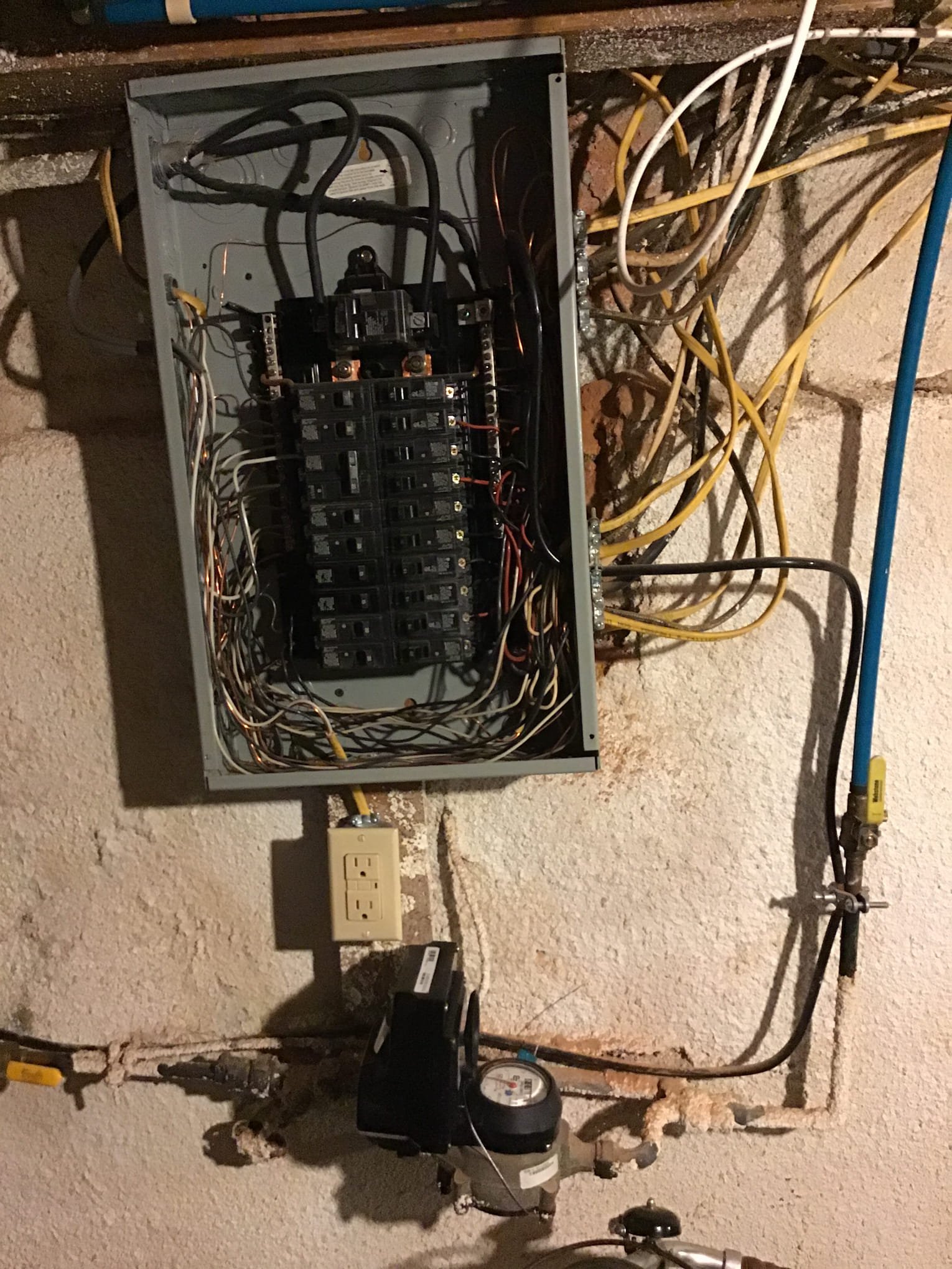 Outdated electrical breaker panel with tangled wiring in a basement before upgrade during a Philadelphia electrical rewire project.