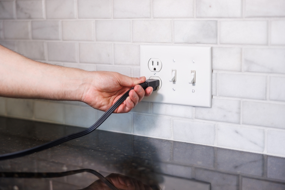 Homeowner unplugging appliance from buzzing outlet.