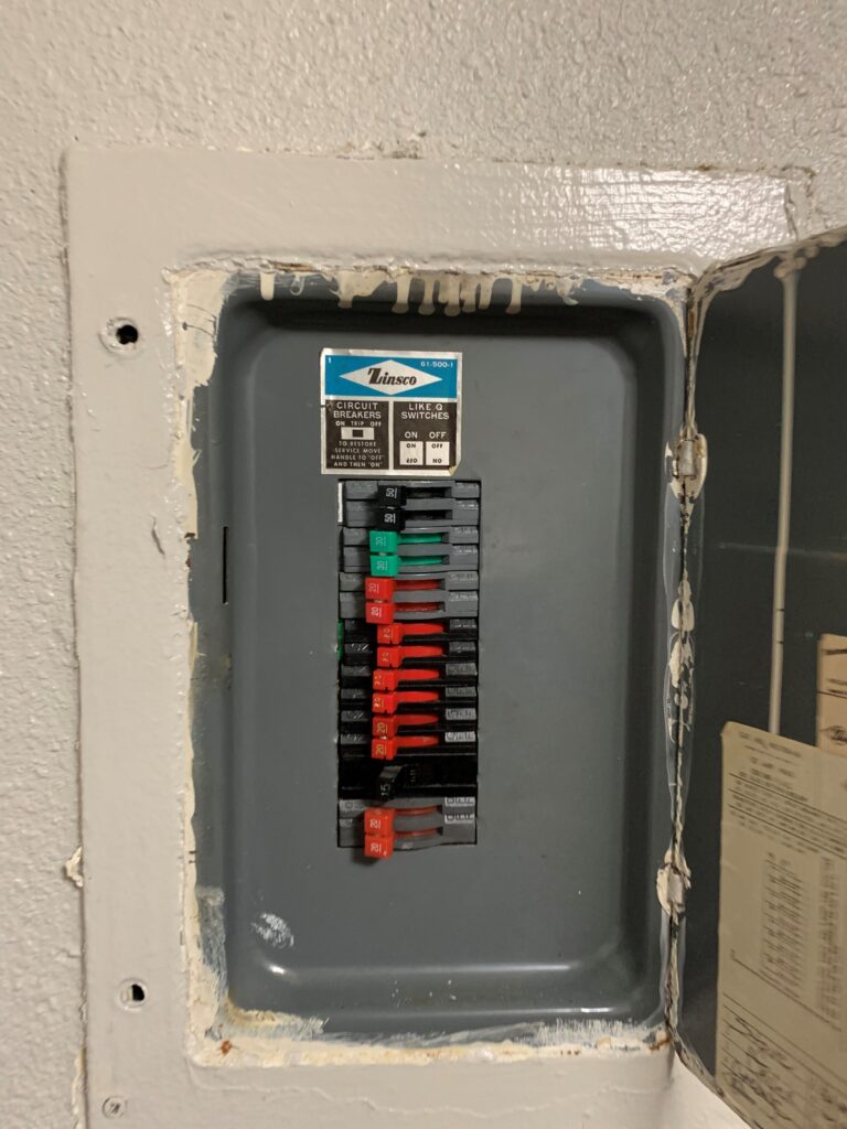 Zinsco electrical panel with colored breaker handles and label inside a wall-mounted metal box, an outdated residential breaker panel known for overheating and failure to trip.