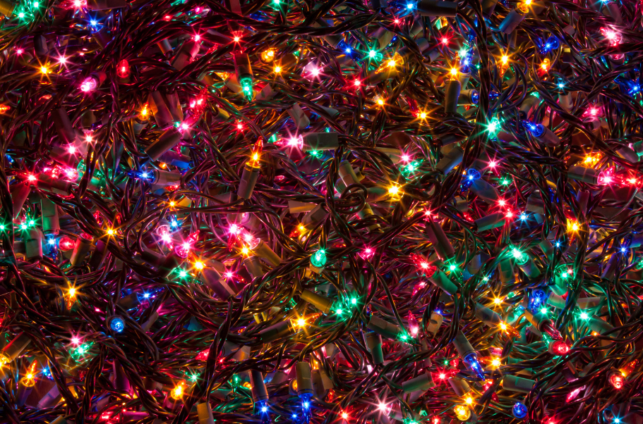 Close-up of colorful holiday string lights tangled together, showing potential electrical overload hazards.