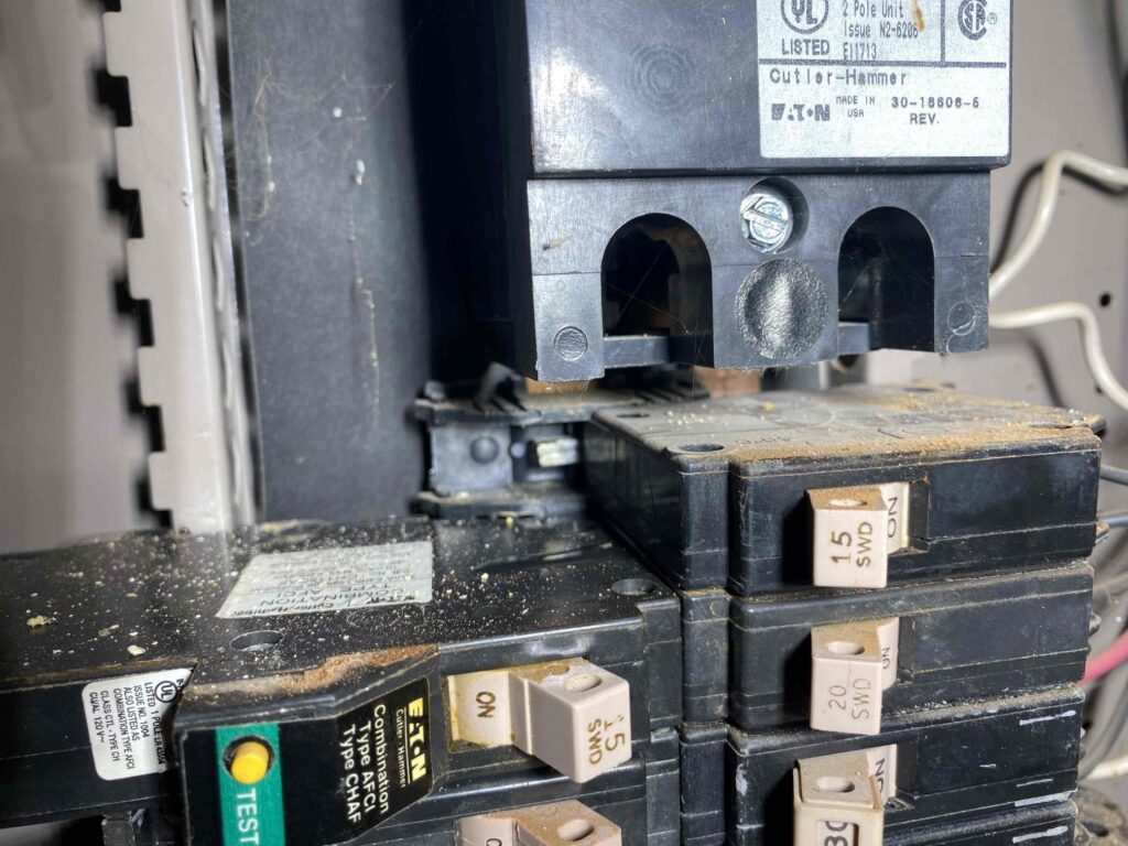 Close-up of damaged circuit breakers and corrosion inside an electrical panel during an electrical service replacement in Philadelphia
